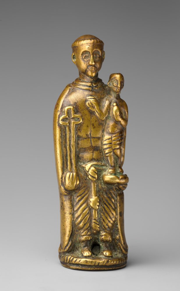 A small cast brass pendant of a standing saint holding a child.