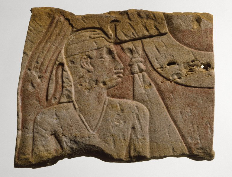 Sandstone temple relief showing a small royal figure under the protection of a goddess.