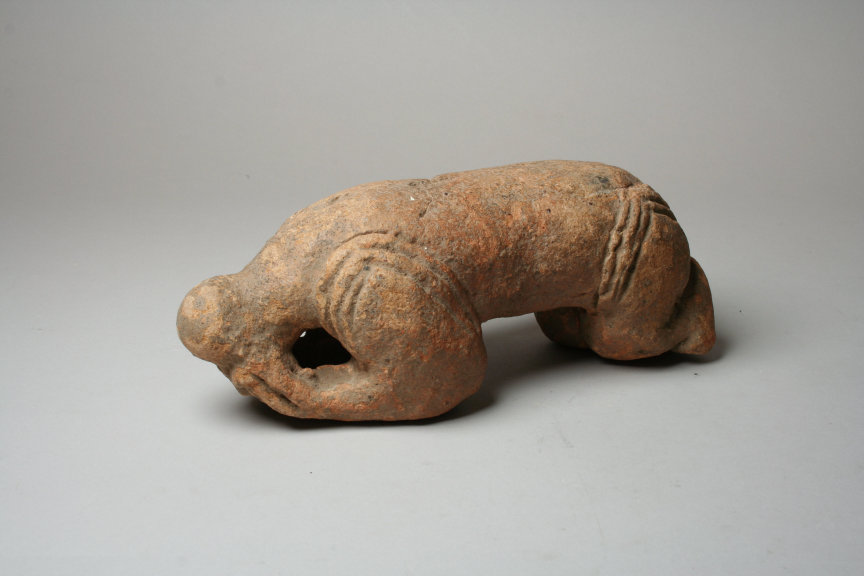 A terracotta figure crouching with the knees drawn up.