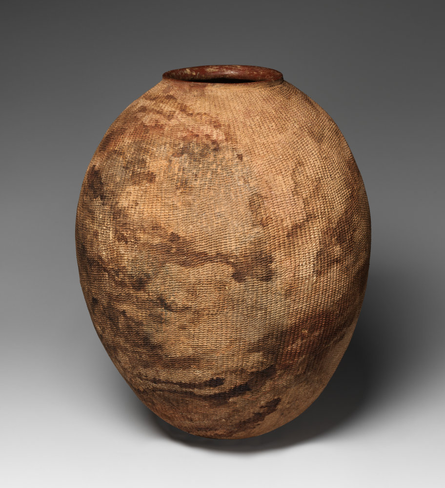 A rounded terracotta vessel covered in impressed decoration.