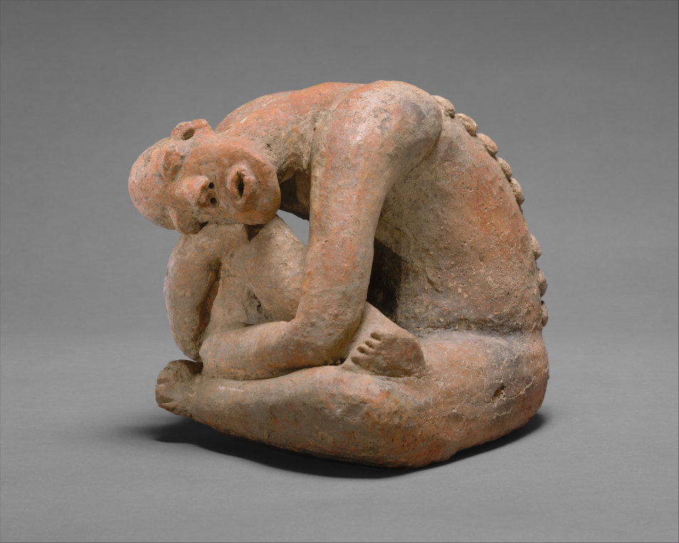 A terracotta figure seated with one leg hugged to the chest and the head dropped on the knee.