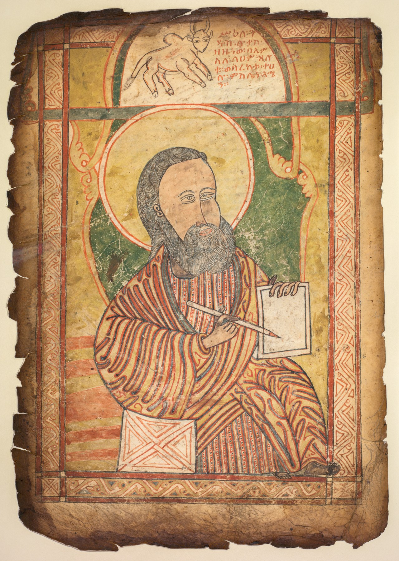 A worn parchment manuscript leaf with a full-page painting of a seated, haloed, bearded man writing in a book, with an ox above him inside an arched frame and an interlace border.