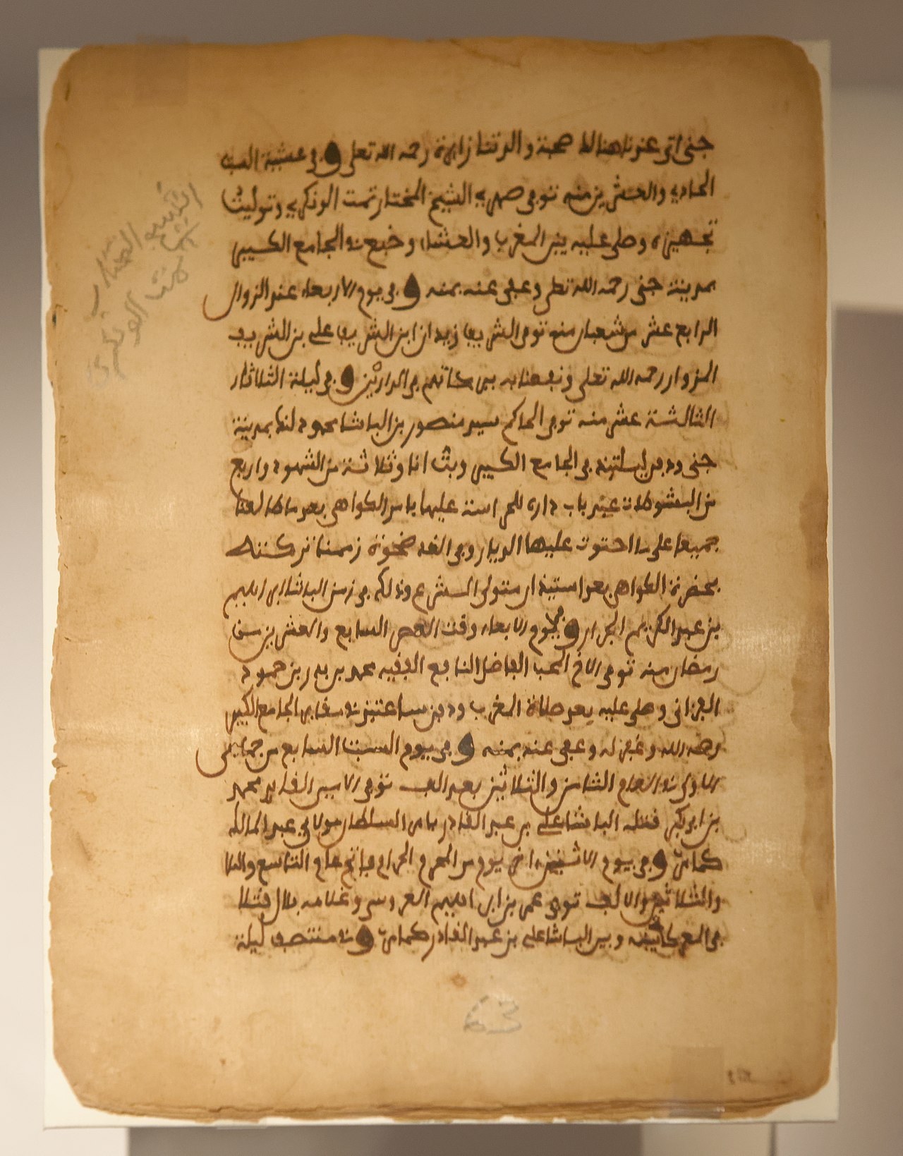 A single page of brown parchment covered in dense lines of Arabic handwriting, with notes in the margin.